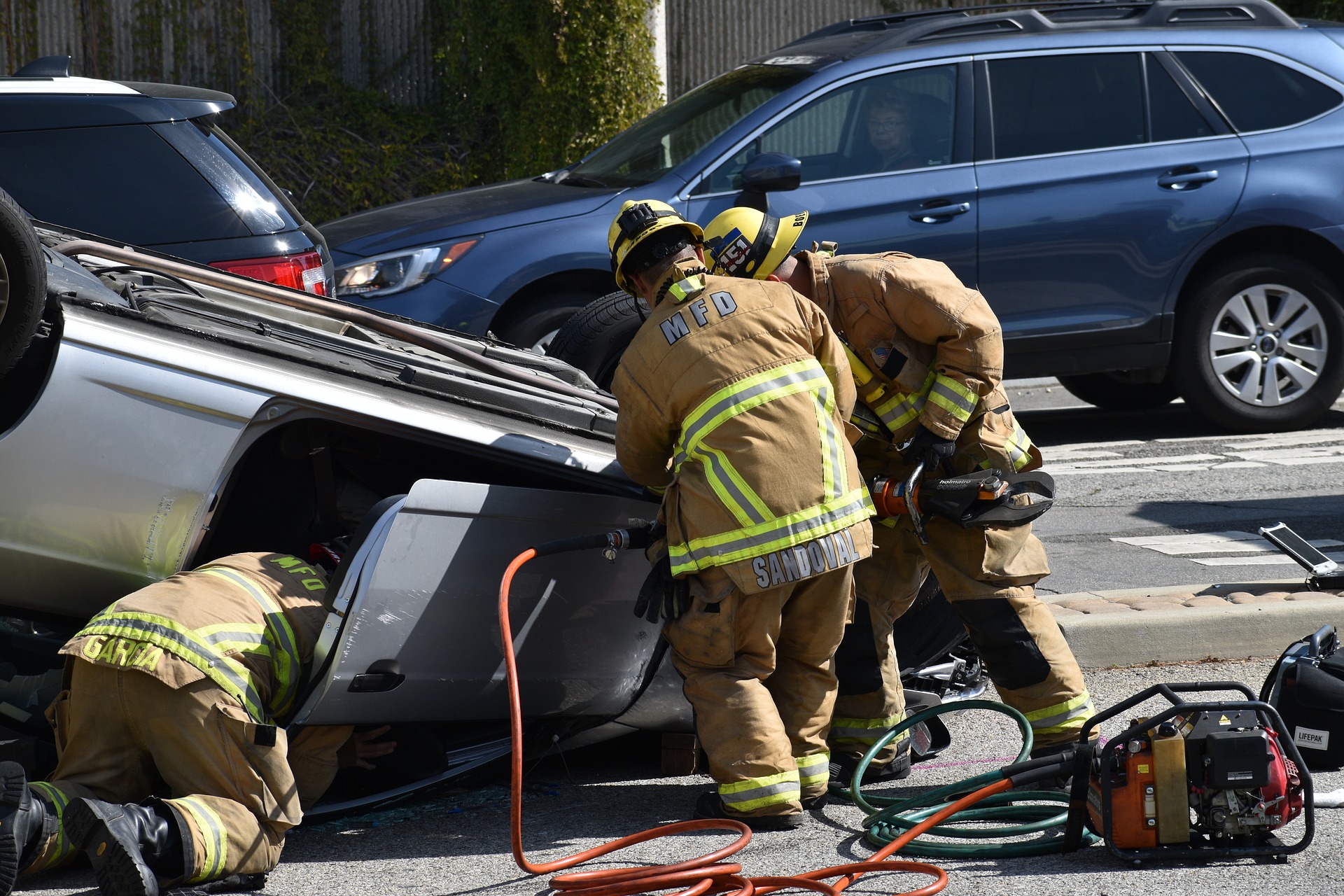 Firefighters rescuing victims from an overturned vehicle after an accident.